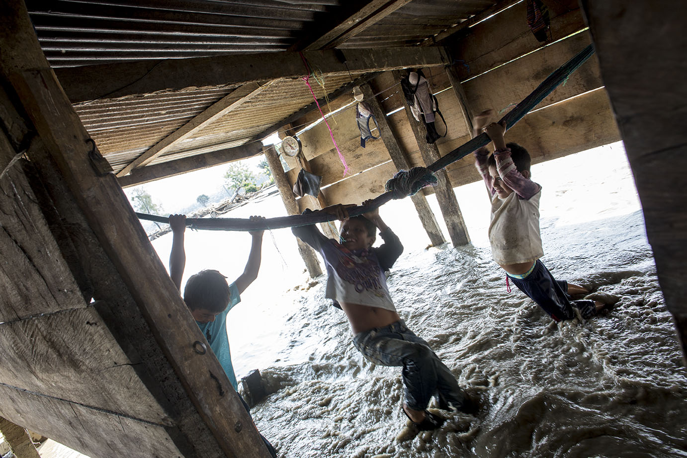 Efron Zebedeo Yac, Kevin Coc y José Raul Botzoc juegan jalándose de la hamaca que quedó en la casa destruida del primer niño, atravesada por el agua desbordada del río Zarco, el 13 de noviembre, en el Valle del Polochic. Simone Dalmasso