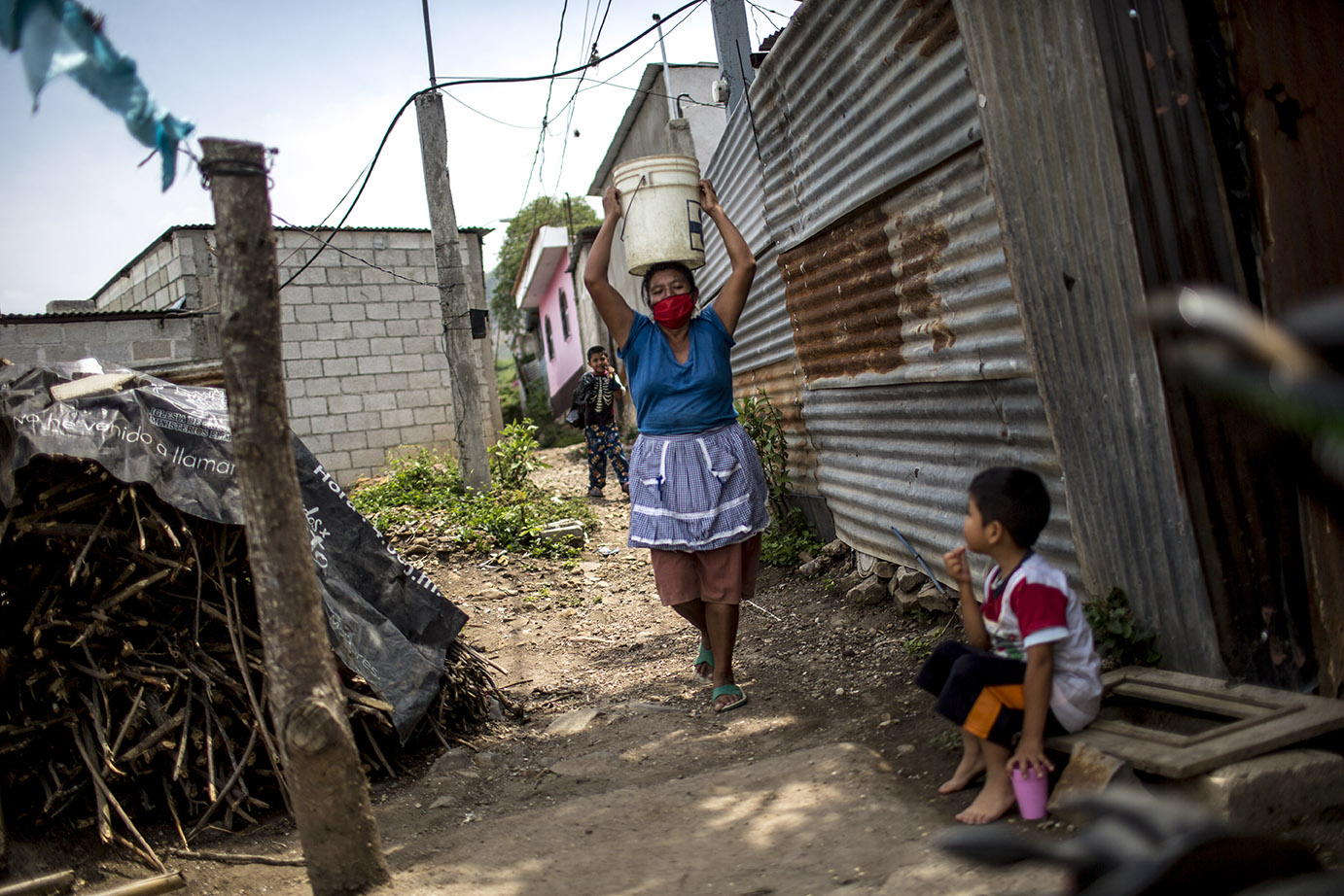 Norma Idalia Ciam de Guamuch, 50, acarrea agua hacia su casa, en la aldea Lo de Rodríguez, sector 2 Vuelta Grande, zona 18 capitalina, durante una distribución de agua por parte de Empagua, en mayo 2020. Simone Dalmasso