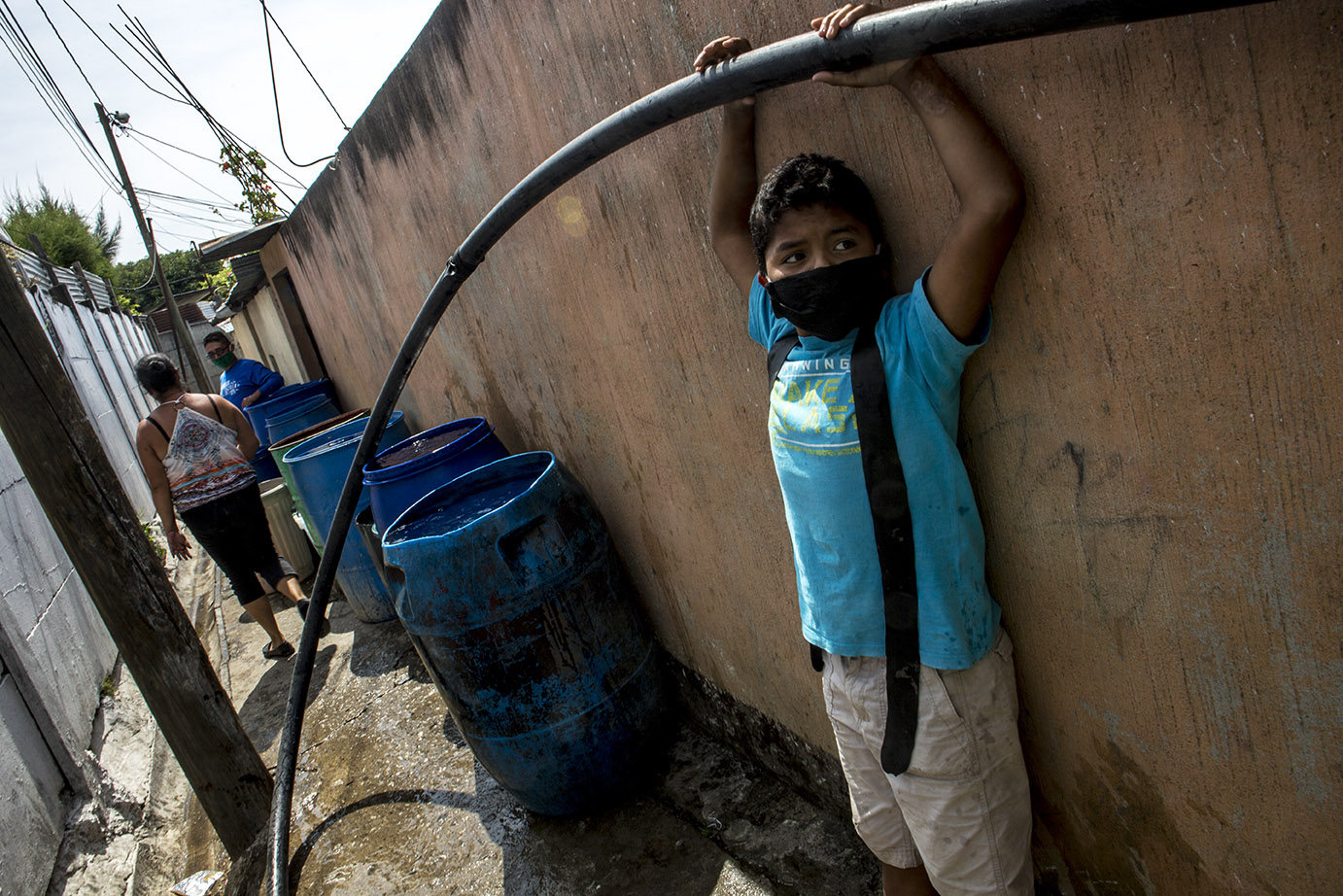 Daniel López, 12, sujeta la manguera que trae agua a los toneles frente de su casa, en la colonia Candelaria, zona 18 capitalina, en mayo 2020, durante una distribución de agua por parte de Empagua. Simone Dalmasso
