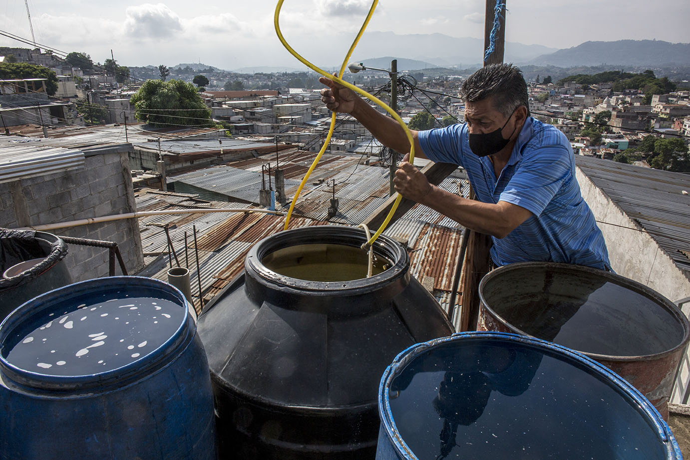 Isidro Ortiz Ascuc, 58, llena de agua los toneles en la terraza de su casa, en la colonia Candelaria, zona 18 capitalina, durante una distribución de agua, en mayo 2020. Simone Dalmasso