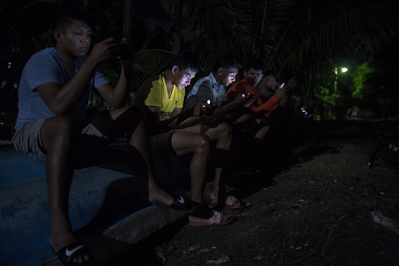 Jóvenes de El Quetzalito se reúnen, por la noche, a la orilla del río Motagua, donde mejor señal de internet se recibe, para jugar en conjunto videojuegos en línea. Simone Dalmasso