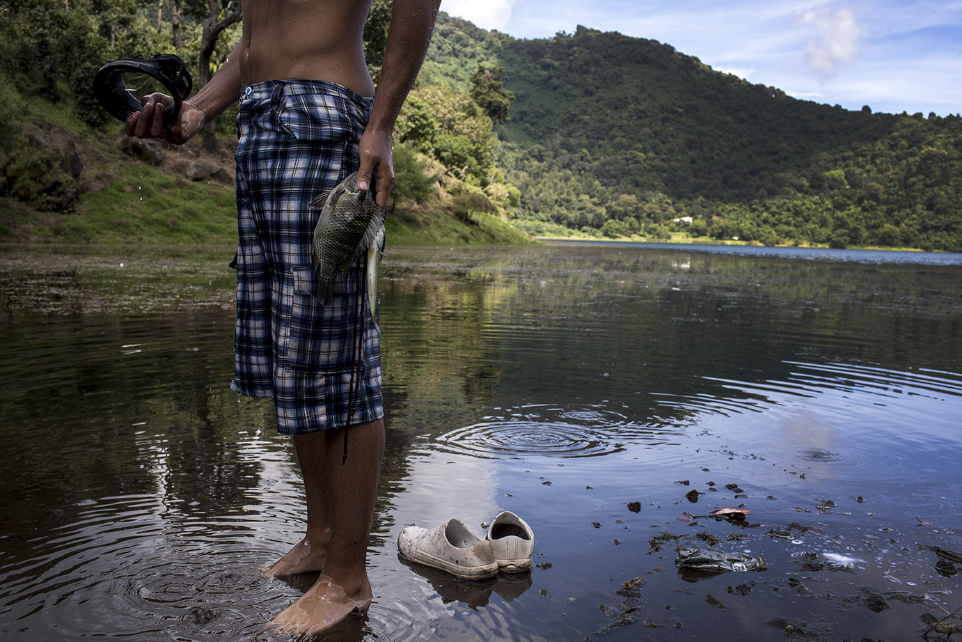 Jairo Guzmán, 19, enseña la mojarra recién pescada. Tal como su padre, el joven sigue la tradición familiar de bucear con arpón, en la laguna de Calderas, octubre 2019. Simone Dalmasso