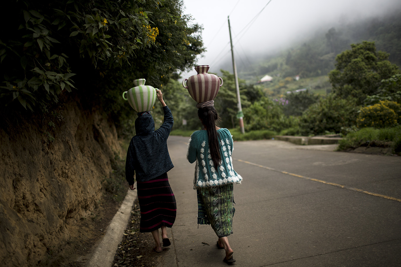 Dos mujeres vuelven a su casa después de haber llenado sus ánforas en un grifo público de la comunidad, en Vuelta Grande